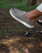 Brown shoe with white sole on a natural ground background