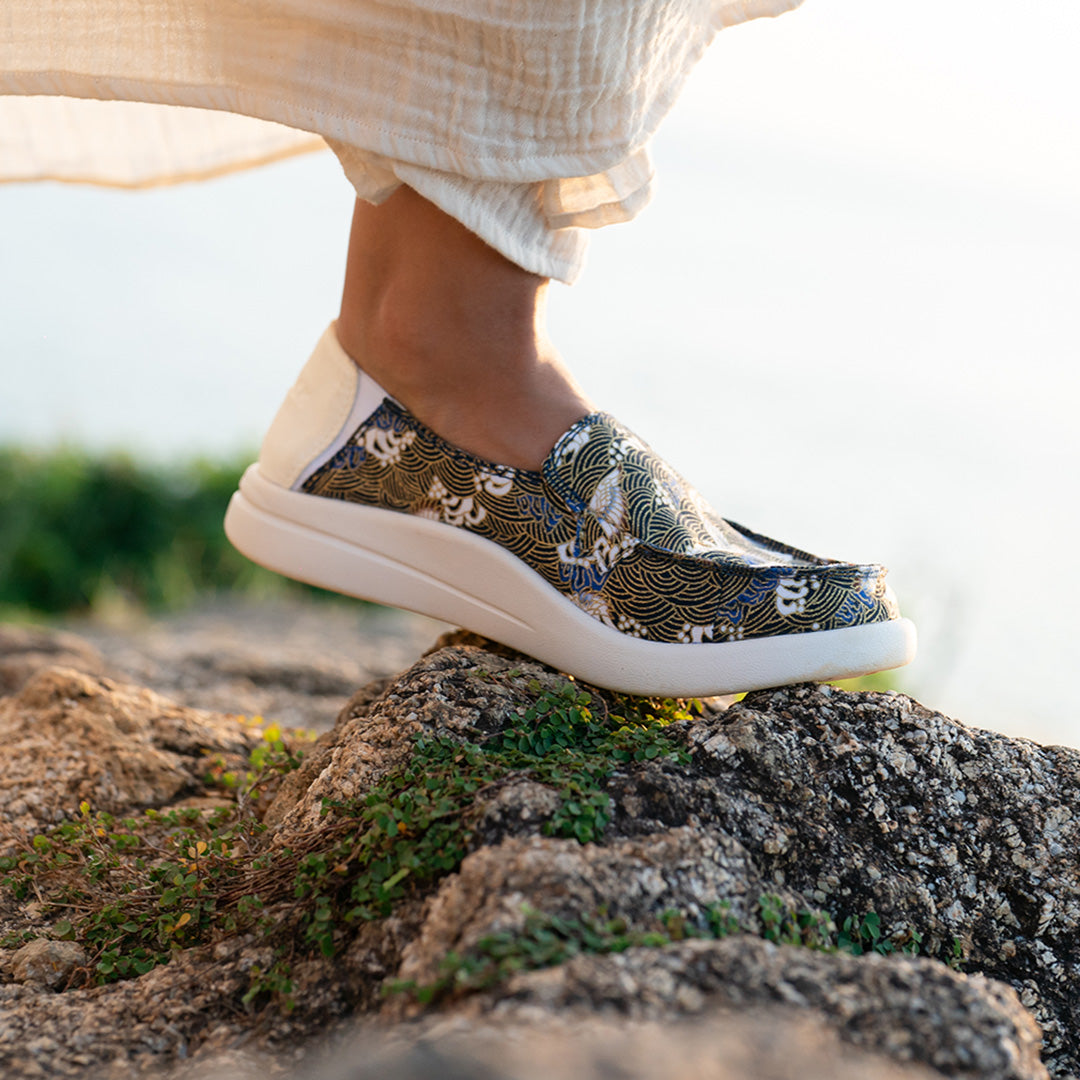 Women wearing floral-patterned KickBack slip-on shoes on a holiday while walking on a rocky surface